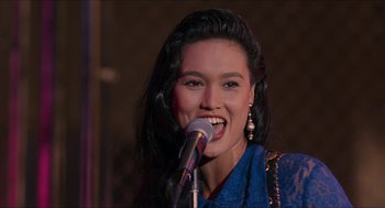 Movie still from “Wayne's World” (1992), directed by Penelope Spheeris – A woman with long black hair singing into a microphone; Close Up shot, Over the shoulder angle