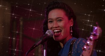 Movie still from “Wayne's World” (1992), directed by Penelope Spheeris – A woman is singing into a microphone in front of a crowd; Close Up shot, Low angle