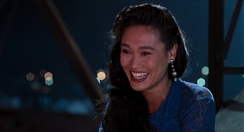Movie still from “Wayne's World” (1992), directed by Penelope Spheeris – A woman smiles brightly as she sits in front of a mirror; Close Up shot, Over the shoulder angle
