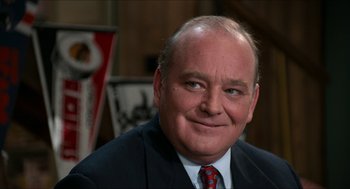 Movie still from “Wayne's World” (1992), directed by Penelope Spheeris – A person wearing a suit and tie; Close Up shot, Over the shoulder angle