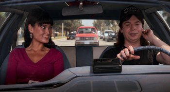 Movie still from “Wayne's World” (1992), directed by Penelope Spheeris – A man and a woman sitting in the driver's seat of a car; Medium shot, Over the shoulder angle