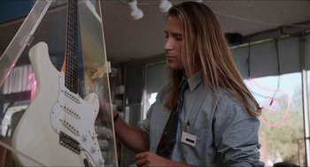 Movie still from “Wayne's World” (1992), directed by Penelope Spheeris – A man with long blonde hair is holding a guitar; Medium shot, Low angle