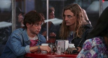 Movie still from “Wayne's World” (1992), directed by Penelope Spheeris – Two men sitting at a table in front of each other; Medium shot, Low angle