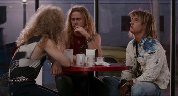Movie still from “Wayne's World” (1992), directed by Penelope Spheeris – A group of people sitting at a table with drinks; Medium shot, Over the shoulder angle
