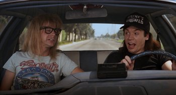 Movie still from “Wayne's World” (1992), directed by Penelope Spheeris – A couple of people in the back seat of a car; Medium shot, Overhead angle