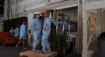 Movie still from “Wayne's World” (1992), directed by Penelope Spheeris – A couple of people standing next to a forklift; Wide shot, Low angle