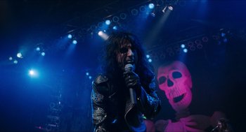 Movie still from “Wayne's World” (1992), directed by Penelope Spheeris – A man with long black hair is holding a microphone; Medium shot, Low angle