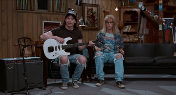 Movie still from “Wayne's World” (1992), directed by Penelope Spheeris – A couple of people that are sitting down with guitars; Wide shot, High angle