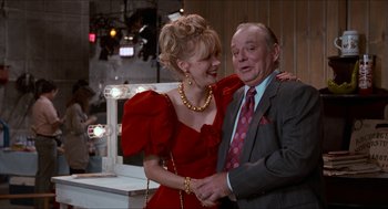 Movie still from “Wayne's World” (1992), directed by Penelope Spheeris – A man and a woman are holding each other; Medium shot, Over the shoulder angle