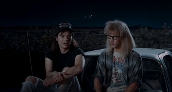 Movie still from “Wayne's World” (1992), directed by Penelope Spheeris – A couple of men sitting next to each other; Medium shot, High angle