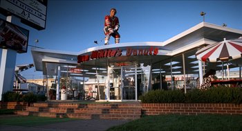 Movie still from “Wayne's World” (1992), directed by Penelope Spheeris – A statue of a hockey player in front of a building; Extreme Wide shot, Low angle