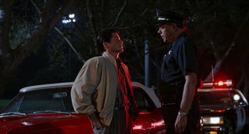 Movie still from “Wayne's World” (1992), directed by Penelope Spheeris – A police officer talking to a man on the side of the road; Medium shot, Over the shoulder angle