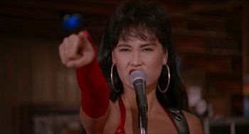 Movie still from “Wayne's World” (1992), directed by Penelope Spheeris – A woman in a red top is holding a microphone; Close Up shot, Over the shoulder angle