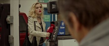 Movie still from “We Summon the Darkness” (2019), directed by Marc Meyers – A woman holding onto a gas nozzles at a gas pump; Medium shot, Over the shoulder angle