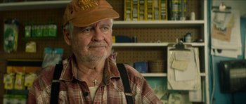 Movie still from “We Summon the Darkness” (2019), directed by Marc Meyers – An older man wearing a plaid shirt and a hat; Close Up shot, Over the shoulder angle