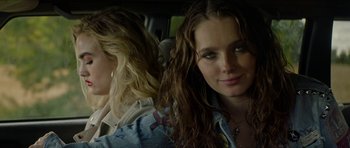 Movie still from “We Summon the Darkness” (2019), directed by Marc Meyers – Two women sitting in the back of a car; Close Up shot, Over the shoulder angle