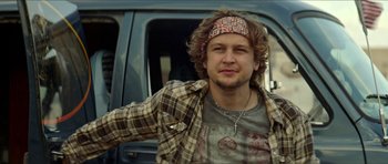 Movie still from “We Summon the Darkness” (2019), directed by Marc Meyers – A man with a bandana on his head leaning against a truck; Close Up shot, Low angle
