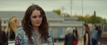 Movie still from “We Summon the Darkness” (2019), directed by Marc Meyers – A woman with long brown hair wearing a jean jacket; Close Up shot, Over the shoulder angle