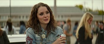 Movie still from “We Summon the Darkness” (2019), directed by Marc Meyers – A woman holding a drink in her hand; Close Up shot, Over the shoulder angle