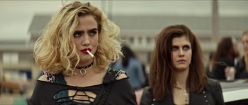 Movie still from “We Summon the Darkness” (2019), directed by Marc Meyers – A woman with a cigarette standing next to another woman; Close Up shot, Over the shoulder angle