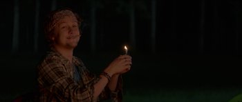 Movie still from “We Summon the Darkness” (2019), directed by Marc Meyers – A person holding a lit candle in their hands; Medium shot, Low angle