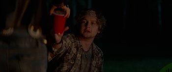 Movie still from “We Summon the Darkness” (2019), directed by Marc Meyers – A man holding up a red cup in a dark room; Close Up shot, Over the shoulder angle