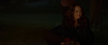 Movie still from “We Summon the Darkness” (2019), directed by Marc Meyers – A woman sitting on the ground in the dark; Medium shot, Over the shoulder angle