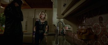 Movie still from “We Summon the Darkness” (2019), directed by Marc Meyers – A woman standing in a kitchen next to a sink; Medium shot, Over the shoulder angle