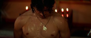 Movie still from “We Summon the Darkness” (2019), directed by Marc Meyers – A man with a necklace is standing in front of candles; Close Up shot, High angle