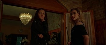Movie still from “We Summon the Darkness” (2019), directed by Marc Meyers – Two women in leather jackets holding knives in a room; Medium shot, Over the shoulder angle