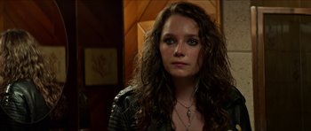 Movie still from “We Summon the Darkness” (2019), directed by Marc Meyers – A person with curly hair wearing a leather jacket; Close Up shot, Over the shoulder angle