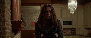 Movie still from “We Summon the Darkness” (2019), directed by Marc Meyers – A woman with long curly brown hair wearing a leather jacket; Medium shot, Over the shoulder angle