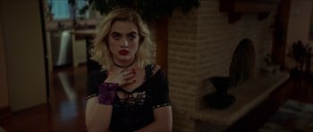 Movie still from “We Summon the Darkness” (2019), directed by Marc Meyers – A woman in a black top with red lipstick; Close Up shot, Over the shoulder angle