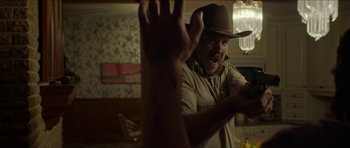 Movie still from “We Summon the Darkness” (2019), directed by Marc Meyers – A man wearing a cowboy hat is looking at his cell phone; Medium shot, Over the shoulder angle