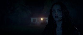 Movie still from “We Summon the Darkness” (2019), directed by Marc Meyers – A woman standing in the dark outside of a house; Close Up shot, Over the shoulder angle