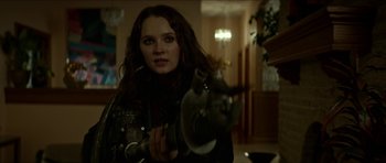 Movie still from “We Summon the Darkness” (2019), directed by Marc Meyers – A woman is holding a gun in a room; Close Up shot, Over the shoulder angle
