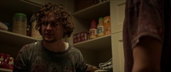 Movie still from “We Summon the Darkness” (2019), directed by Marc Meyers – A man with curly blonde hair is in a kitchen; Close Up shot, Low angle