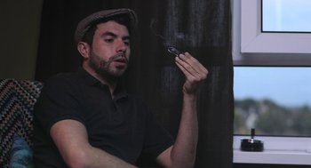Movie still from “Weekend” (2011), directed by Andrew Haigh – A bearded man holding a cigarette in his hand; Medium shot, Low angle