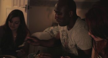 Movie still from “Weekend” (2011), directed by Andrew Haigh – A man sitting at a table eating food; Medium shot, Over the shoulder angle