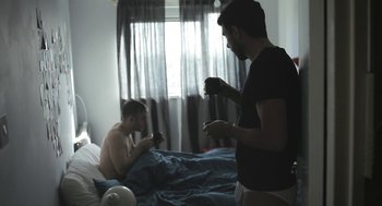 Movie still from “Weekend” (2011), directed by Andrew Haigh – Two men are playing a video game in a bedroom; Medium shot, Over the shoulder angle