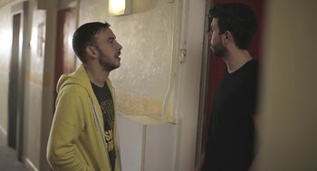 Movie still from “Weekend” (2011), directed by Andrew Haigh – Two young men standing next to each other in front of a door; Medium shot, Over the shoulder angle