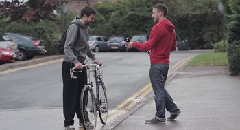 Movie still from “Weekend” (2011), directed by Andrew Haigh – Two young men standing on the side of the road with bicycles; Medium shot, Over the shoulder angle