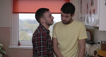 Movie still from “Weekend” (2011), directed by Andrew Haigh – Two men standing next to each other in front of a window; Medium shot, High angle