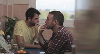 Movie still from “Weekend” (2011), directed by Andrew Haigh – Two young men sitting at a table eating food; Medium shot, Over the shoulder angle
