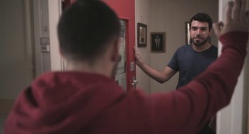 Movie still from “Weekend” (2011), directed by Andrew Haigh – Two people standing in front of a red door; Medium shot, Over the shoulder angle
