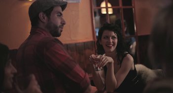 Movie still from “Weekend” (2011), directed by Andrew Haigh – A man and a woman sitting at a table with a drink; Medium shot, Over the shoulder angle