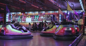 Movie still from “Weekend” (2011), directed by Andrew Haigh – A group of people riding bumper cars at a carnival; Extreme Wide shot, High angle