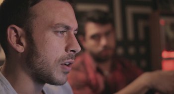 Movie still from “Weekend” (2011), directed by Andrew Haigh – A man with a goatee is looking into the distance; Close Up shot, Over the shoulder angle