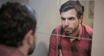 Movie still from “Weekend” (2011), directed by Andrew Haigh – A man looking at himself in the mirror; Close Up shot, Over the shoulder angle
