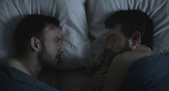 Movie still from “Weekend” (2011), directed by Andrew Haigh – Two men in a bed with pillows and a blanket; Close Up shot, Overhead angle